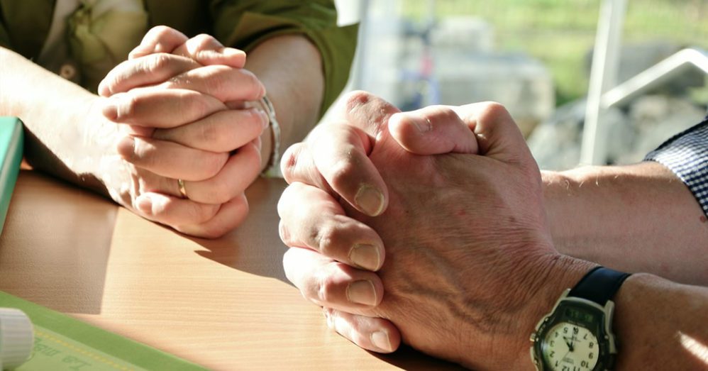 Man and a women close of hands praying together
