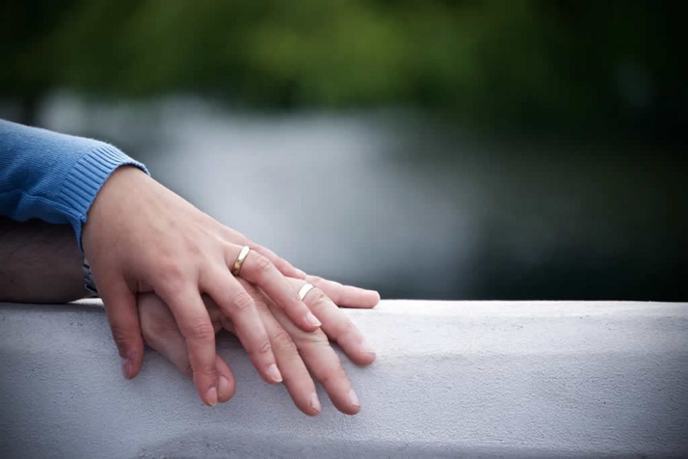 Married couple holding hands over a ledge